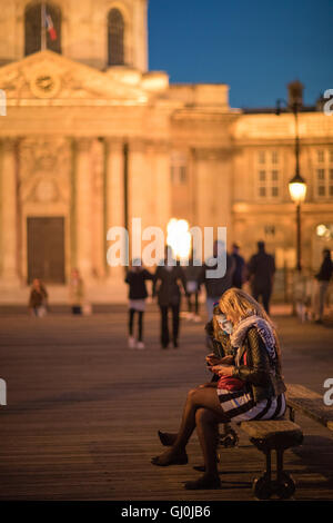 Deux femmes sur leurs téléphones portables sur le Pont des Arts, au crépuscule, Paris, France Banque D'Images