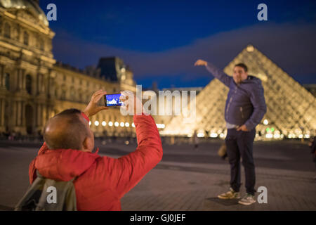 Les touristes de prendre des photos au palais du Louvre, au crépuscule, Paris, France Banque D'Images