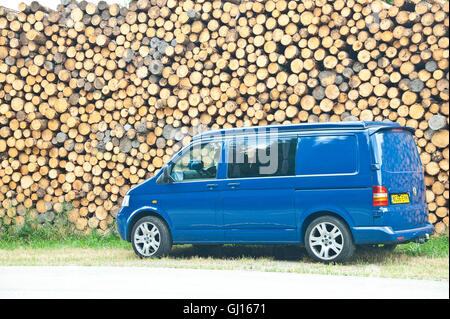 Vw Transporter T5 camper van garé en face d'une pile de grumes coupées Banque D'Images