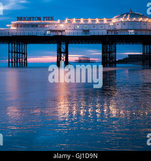 Brighton Pier au crépuscule reflète dans le sable humide de la marée basse. Dans la distance de l'ancienne jetée Ouest peut être vu. Banque D'Images