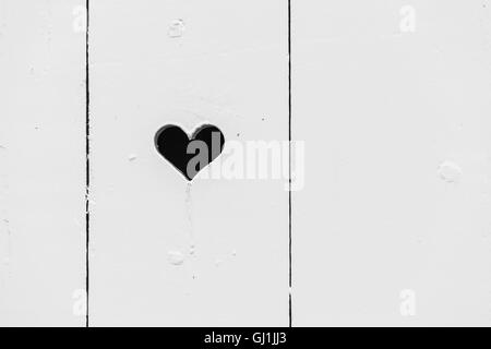 Trou en forme de coeur noir en blanc mur en bois, texture de fond photo Banque D'Images