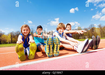 Enfants heureux de faire des exercices d'étirement sur un stade Banque D'Images