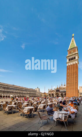 Le clocher ou campanile de la Basilique St Marc, avec tables et chaises de Florian's Cafe au premier plan.Venise, Italie. Banque D'Images