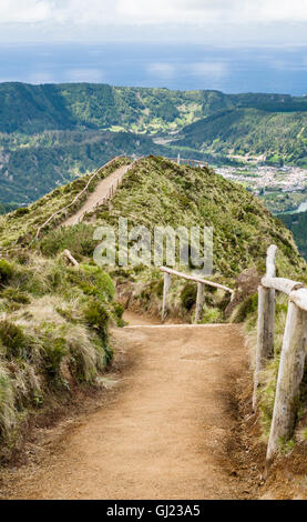 Chemin vers le point de vue. Un chemin de terre avec des mains courantes en bois sur les collines des vents d'une vue spectaculaire au-dessus de Sete Cidades. Banque D'Images