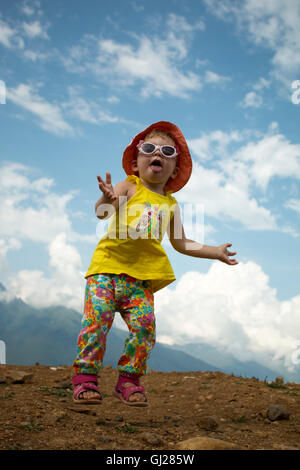 Enfant de sauter sur un fond de ciel bleu dans les montagnes en été Banque D'Images