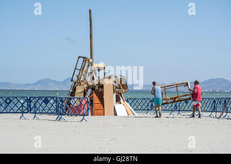 Les hommes d'aider à construire un feu de joie sur la plage de Los Alcazares pour célébrer le solstice d'été, Murcia, Espagne Banque D'Images