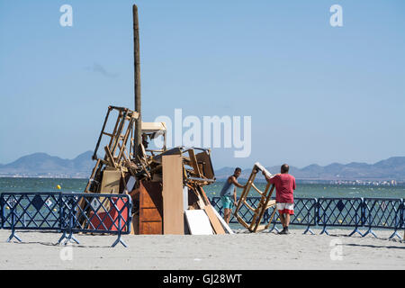 Les hommes d'aider à construire un feu de joie sur la plage de Los Alcazares pour célébrer le solstice d'été, Murcia, Espagne Banque D'Images