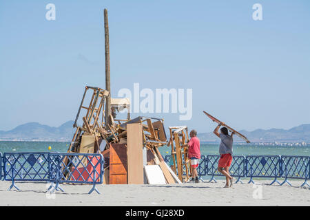 Les hommes d'aider à construire un feu de joie sur la plage de Los Alcazares pour célébrer le solstice d'été, Murcia, Espagne Banque D'Images