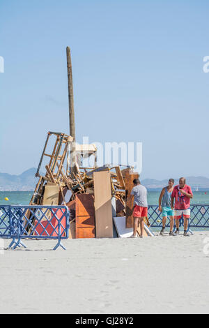 Les hommes d'aider à construire un feu de joie sur la plage de Los Alcazares pour célébrer le solstice d'été, Murcia, Espagne Banque D'Images