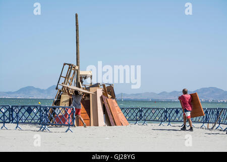 Les hommes d'aider à construire un feu de joie sur la plage de Los Alcazares pour célébrer le solstice d'été, Murcia, Espagne Banque D'Images