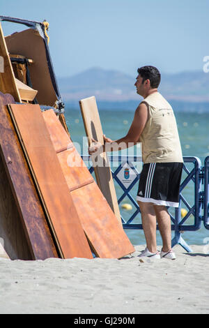 Un homme aide à construire un feu de joie sur la plage de Los Alcazares pour célébrer le solstice d'été, Murcia, Espagne Banque D'Images