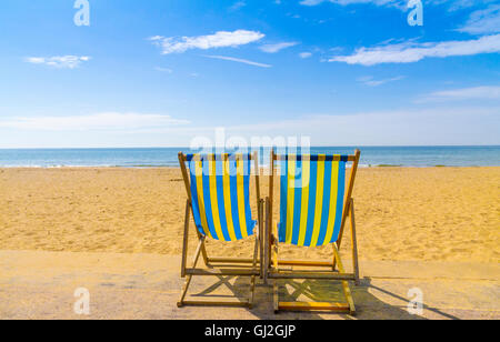 Bleu et jaune deux transats face à la mer à travers le sable doré sur une journée ensoleillée, Bournemouth, Royaume-Uni Banque D'Images