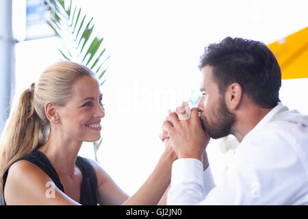 Young couple outdoors, man kissing woman's hands, smiling Banque D'Images