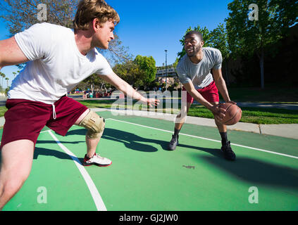 Deux hommes jouant au basket-ball à l'extérieur sur cour Banque D'Images