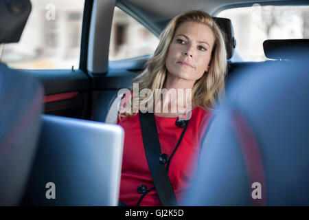 Businesswoman using laptop et à la voiture de siège arrière Banque D'Images