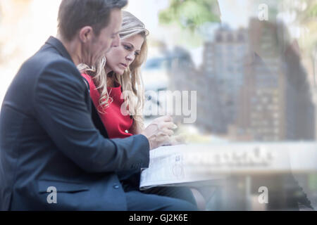 Businessman and woman reading newspaper et bavarder dans city park Banque D'Images