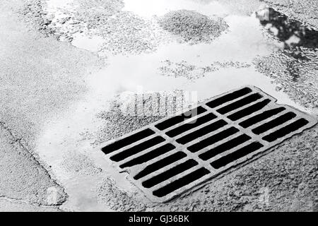 Grille d'égout métallique pour système de drainage sur la route d'asphalte humide Banque D'Images