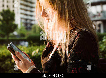 Jeune femme à l'extérieur, using smartphone Banque D'Images