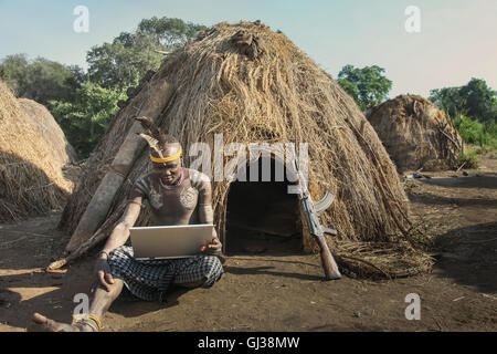 L'homme de la tribu Mursi avec ordinateur portable et d'armes à feu kalachnikov, vallée de l'Omo, Ethiopie Banque D'Images