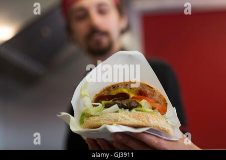 Jeune homme servant hamburger de restauration rapide van Banque D'Images