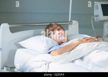 Woman lying on hospital bed looking at camera Banque D'Images