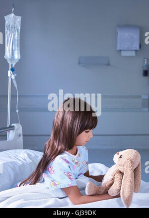 Patient fille regardant sur lapin jouet pour enfants hôpital ward Banque D'Images