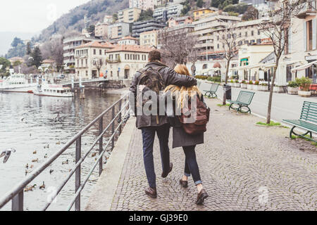 Vue arrière du jeune couple se promener le long du lac, Lac de Côme, Italie Banque D'Images