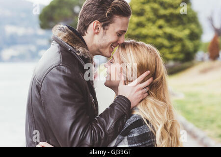 Jeune homme romantique kissing girlfriends front, Lac de Côme, Italie Banque D'Images