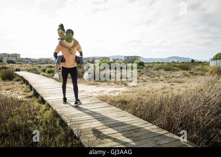 Man giving piggyback ami sur passerelle en bois