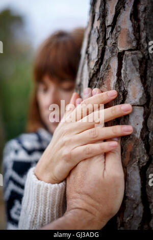 Woman holding mans part hugging tree Banque D'Images