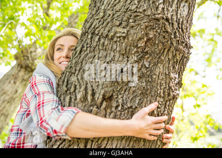 Woman hugging tree smiling Banque D'Images