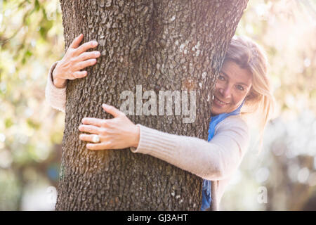 Woman hugging tree smiling at camera Banque D'Images