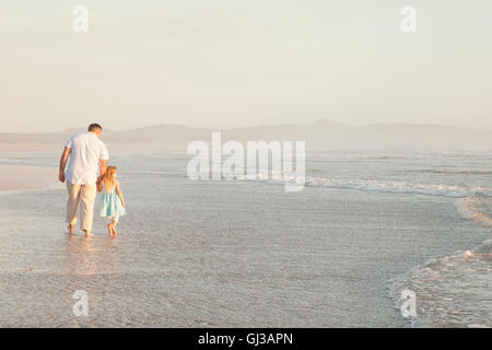 Père et fille se tenant la main en pagayant ocean Banque D'Images