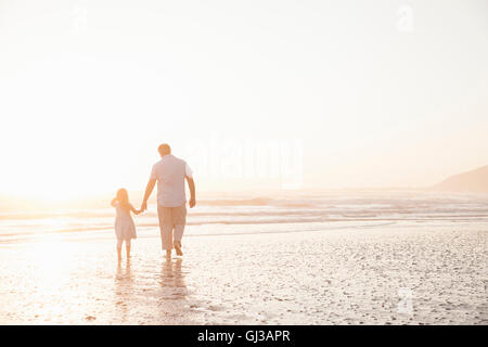 Père et fille se tenant la main en pagayant ocean Banque D'Images