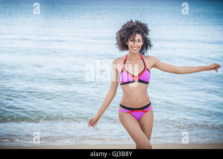 Belle jeune femme portant pink bikini dancing on beach, Costa Rei, Sardaigne, Italie Banque D'Images