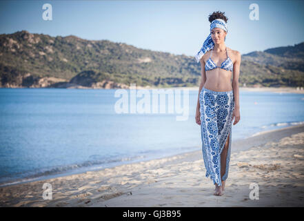 Belle jeune femme wearing bikini top et jupe strolling on beach, Costa Rei, Sardaigne, Italie Banque D'Images