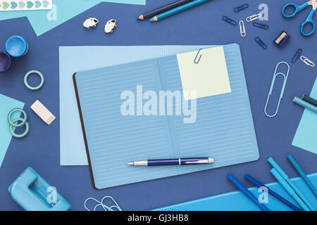 Ordinateur portable ouvert et sticky note sur bleu 24. Fournitures et d'album sur la table. Mise à plat Banque D'Images