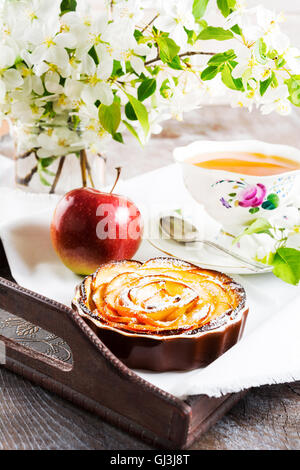 En forme de rose apple pie et une tasse de thé sur le plateau de thé vintage servant le petit-déjeuner avec des pâtisseries sucrées de pomme. Gâteau aux pommes maison Banque D'Images