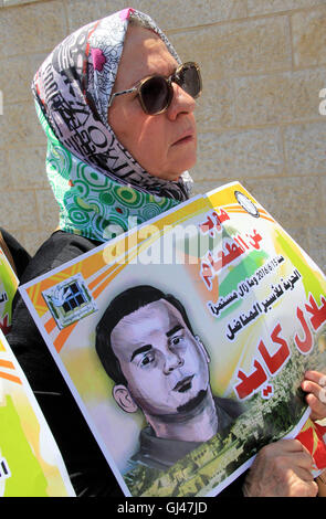 Jérusalem, Jérusalem, territoire palestinien. 12Th Aug 2016. Des manifestants palestiniens tenir affiches contre la détention administrative et à l'appui du prisonnier palestinien Bilal Kayed (portrait), qui avait jeûné pendant près de deux mois au cours de sa détention sans procès, comme ils démontrent à l'extérieur de la Croix-Rouge à Jérusalem est le 12 août 2016. Credit : ZUMA Press, Inc./Alamy Live News Banque D'Images