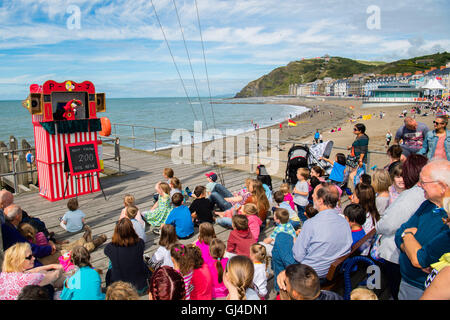 Pays de Galles Aberystwyth UK, le samedi 13 août 2016 UK Weather : les familles et les enfants bénéficiant de regarder un Punch and Judy show traditionnel dans le chaud soleil d'été à l'assemblée annuelle de la rive de la mer festival alimentaire sur la promenade de Aberystwyth, sur la côte ouest du pays de Galles. Après une semaine de froid et venteux, le temps est réglé à améliorer au cours des prochains jours, jusqu'à une mini-canicule le mardi, avec des températures qui devraient atteindre la haute ou basse 20s 30s centigrades Crédit photo : Keith Morris/Alamy Live News Banque D'Images