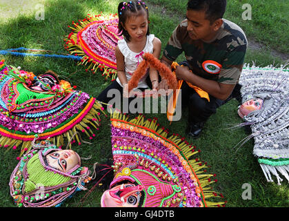 Kolkata, Inde. 13e Août 2016. Un artiste indien montre sa fille des masques de danse avant de prendre part à une répétition générale pour les commémorations de l'indépendance à la Red Road à Kolkata, Inde, le 13 août 2016. L'Inde va célébrer son jour de l'indépendance le 15 août. Credit : Tumpa Mondal/Xinhua/Alamy Live News Banque D'Images