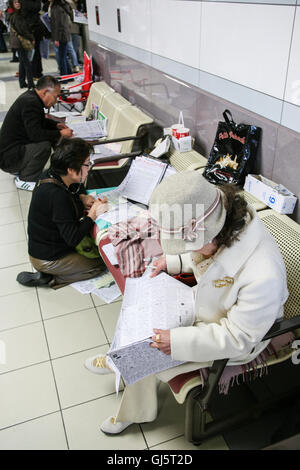 À l'intérieur de l'énorme stand punters contrôle de la forme des chevaux de race 11, la grande course du jour l'American Jockey Club Cup avec de Banque D'Images