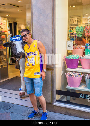 Un homme vêtu d'un touristiques Los Angeles Lakers basketball jersey pose avec une vache grandeur nature artificielle à l'extérieur d'un magasin. Banque D'Images