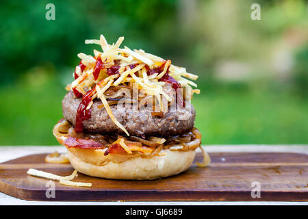 Beefburger avec oignons frits, bacon et frites en chaîne brioche bun Banque D'Images