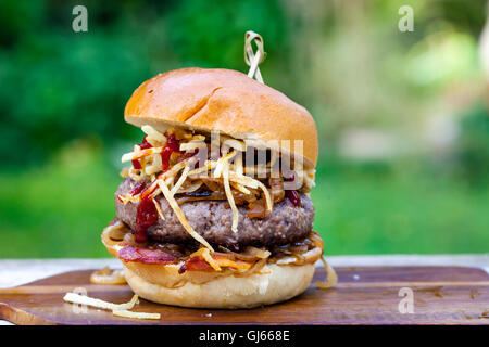 Beefburger avec oignons frits, bacon et frites en chaîne brioche bun Banque D'Images