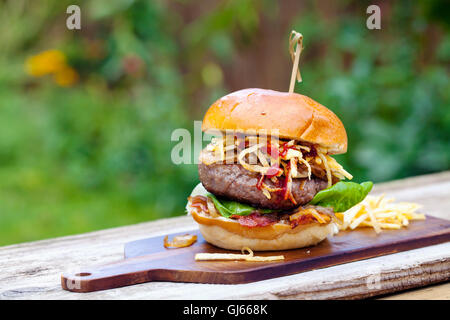 Beefburger avec oignons frits, bacon et frites en chaîne brioche bun Banque D'Images