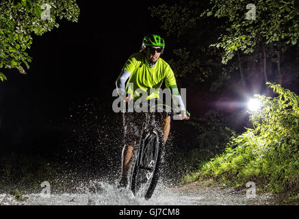 Du vélo de montagne dans la nuit à travers la forêt d'équitation et cours d'eau autour. Vue avant Banque D'Images