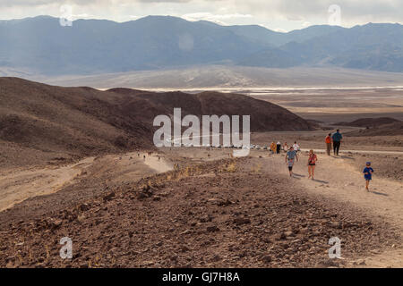 Les touristes de la randonnée jusqu'à les collines volcaniques et sédimentaires près de la palette de l'artiste dans la Death Valley National Park, California, USA Banque D'Images
