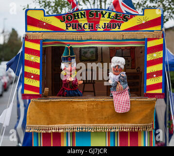 Mr Punch avec Judy tenant le bébé en face d'un Punch and Judy stand marionnettes Banque D'Images