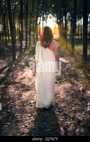 Aqua bleu habillé femme marche dans la forêt et on la voit sur son dos. Banque D'Images